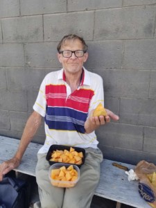 senior man with glasses holding cut up cantaloupe in containers 