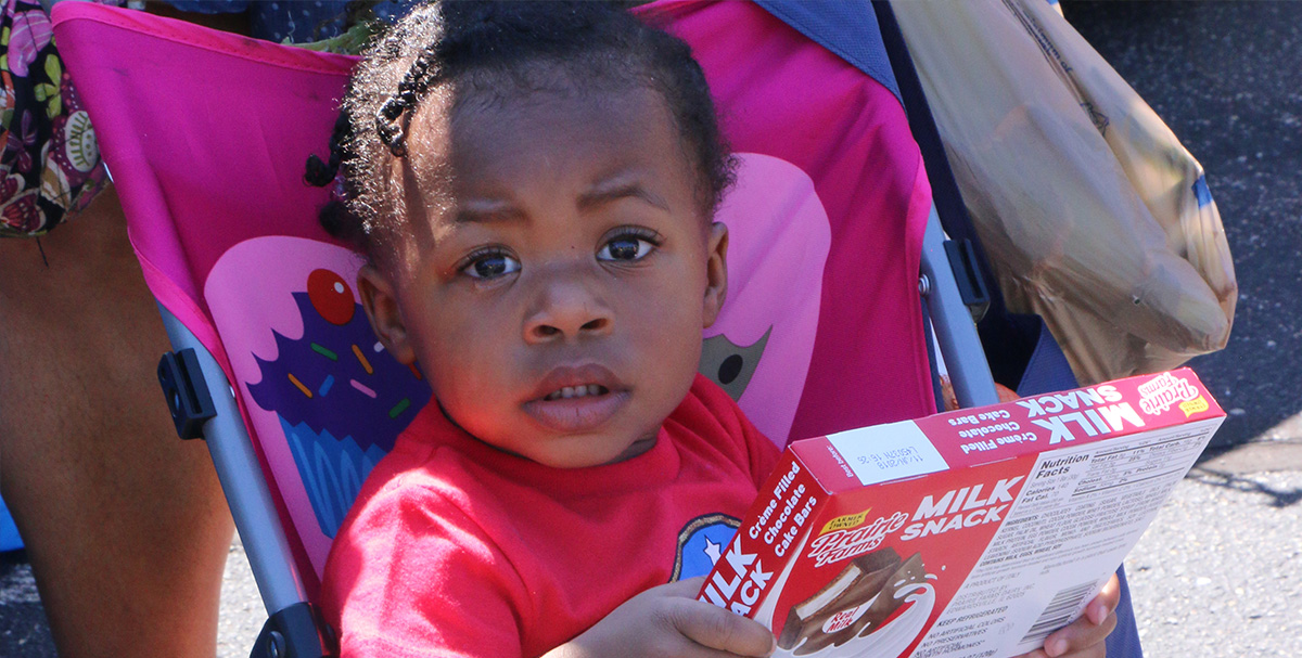 little girl holding milk snack in stroller