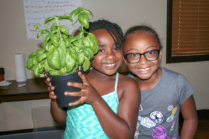 two girls holding basil plant