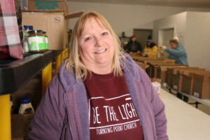 A woman, who volunteers at Turning Point Church's food pantry in Scottsburg, Indiana, smiles for a photo in the pantry.