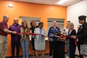 Stakeholders gather to cut a big red ribbon, markingi the grand opening of the Tom and Julie Woof Family Resource Center at Gleaners Food Bank of Indiana.